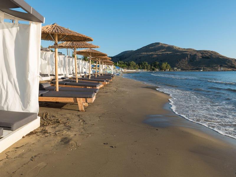 Pusta plaża z leżakami i parasolami obok spokojnego morza i gór w tle