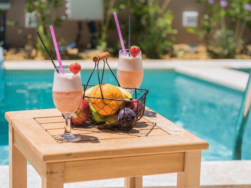 Stół z dwoma koktajlami mlecznymi i świeżymi owocami obok basenu.