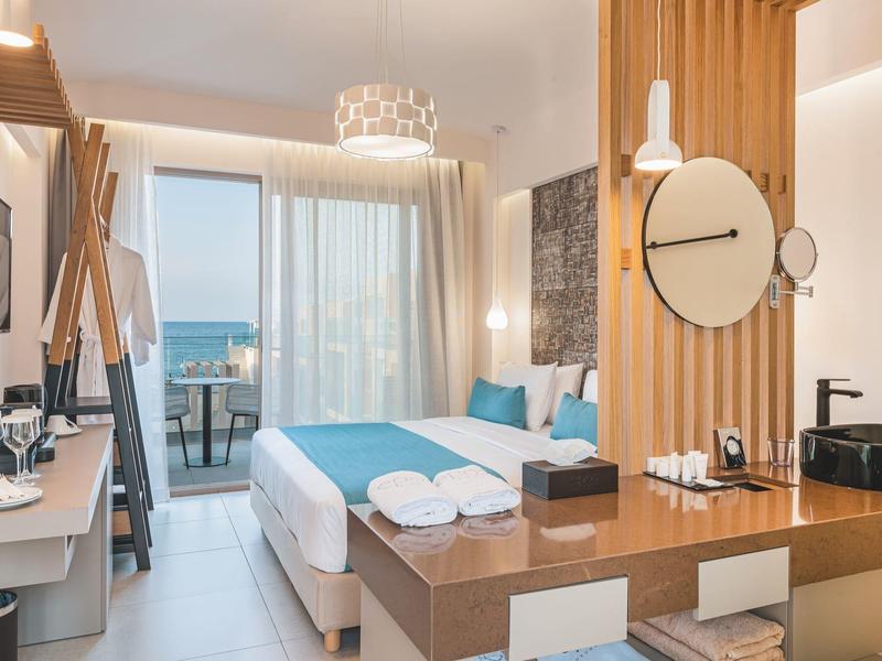 Nowoczesny pokój hotelowy z widokiem na morze i balkonem, jasne kolory i stylowe meble.