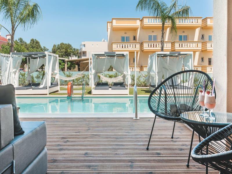 Nowoczesny basen hotelowy z leżakami i częścią wypoczynkową ze stołem i kieliszkami do wina na drewnianym tarasie.