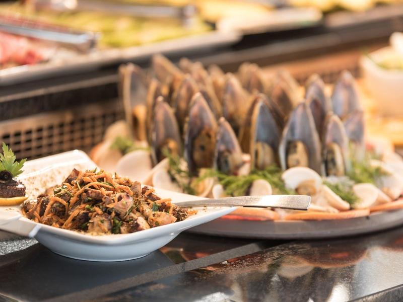 Zbliżenie małży i innych owoców morza na bufecie z talerzem i łyżką.