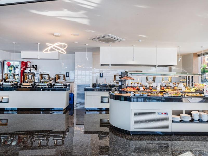 Nowoczesny bufet hotelowy z kawiarnią i stanowiskiem z wypiekami w jasnym, czystym pomieszczeniu.