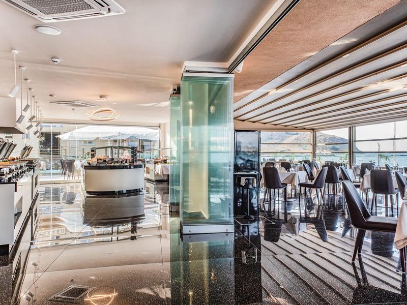 Jasna, nowoczesna przestrzeń restauracyjna hotelu z nakrytymi stołami i panoramicznymi oknami.