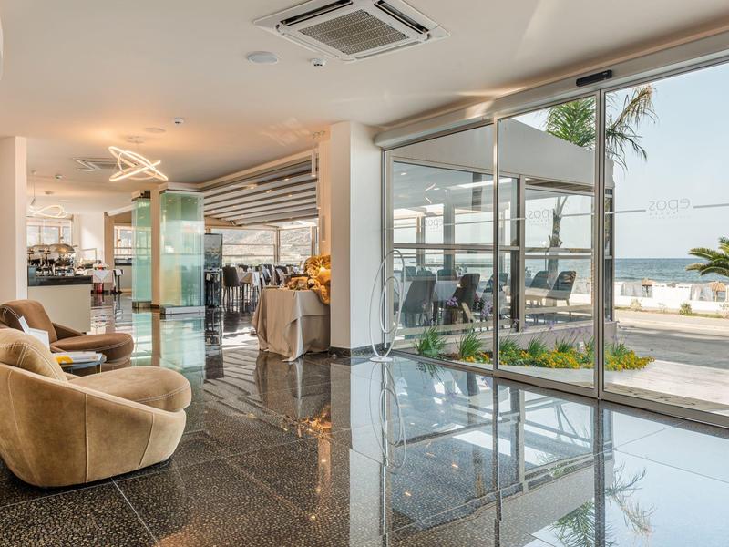 Elegancka lobby hotelowa z dużymi szklanymi oknami z widokiem na basen i wybrzeże.