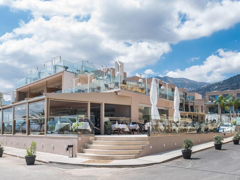 Nowoczesna restauracja hotelowa z tarasem na zewnątrz, stołami i parasolami w słoneczny dzień.