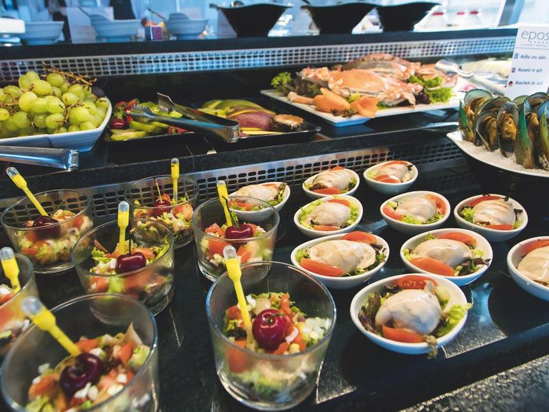 Bufet z różnymi daniami z owoców morza i przekąskami serwowanymi w małych miseczkach.