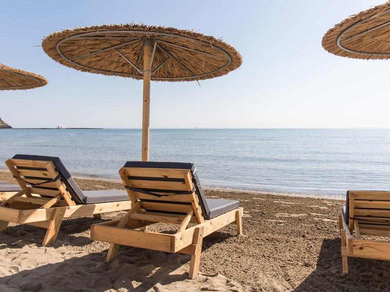 Plaża z parasolami ze słomy i drewnianymi leżakami nad spokojnym morzem