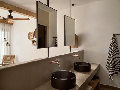 Bagno moderno con due lavandini neri e specchi rettangolari.