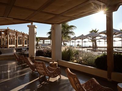 Area spiaggia soleggiata con sedie e ombrelloni vicino alla piscina dell'hotel.