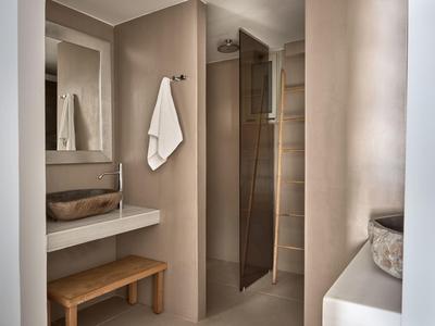 Bagno moderno con lavabo, sgabello in legno e doccia a filo pavimento.