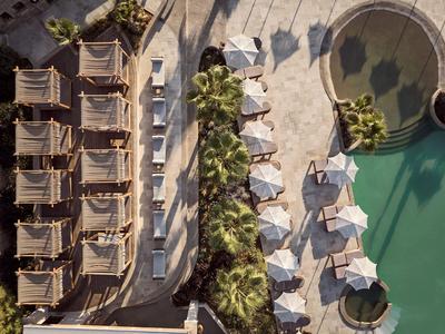 Vista aérea de tumbonas y sombrillas junto a una piscina con sección circular.