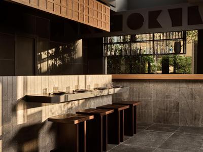 Diseño interior moderno con muebles de madera y paredes de concreto, iluminado por luz natural.