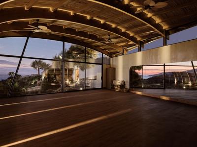 Gran sala vacía con suelo de madera y paredes de vidrio al atardecer