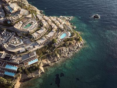 Complesso alberghiero di lusso con più piscine sulla costa rocciosa vicino al mare.