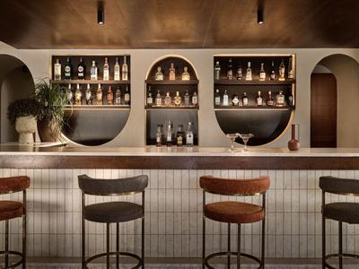 Bar dell'hotel moderno con archi e sgabelli in luce calda.
