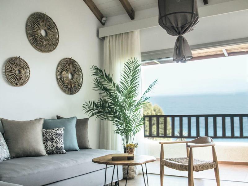 Soggiorno moderno con vista mare, mobili in legno chiaro e zona divano accogliente.