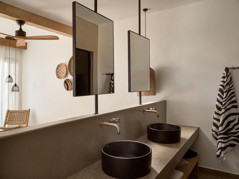 Bagno moderno con due lavandini neri e specchi rettangolari.