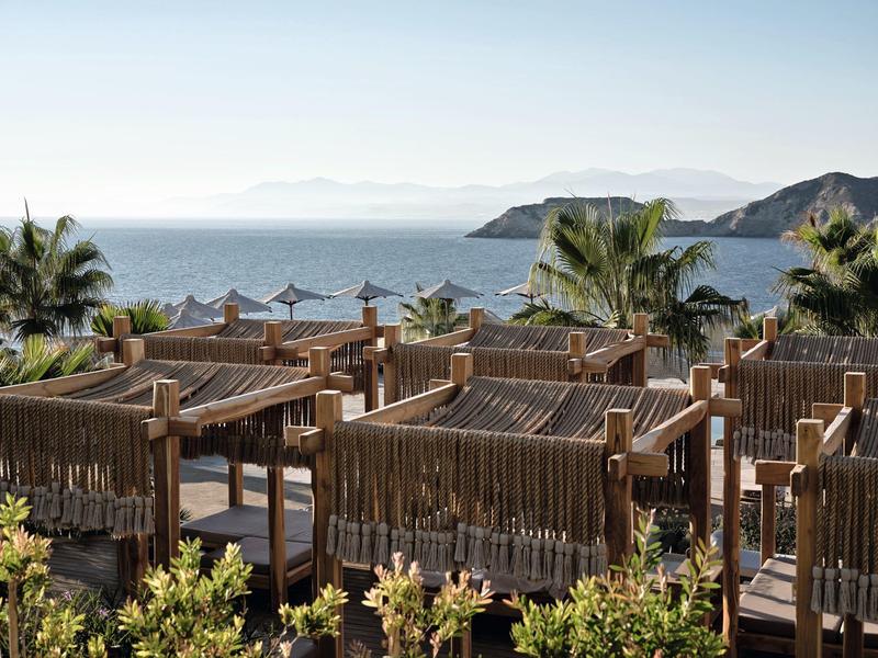 Vista di un resort sulla spiaggia con docce in legno e palme vicino al mare