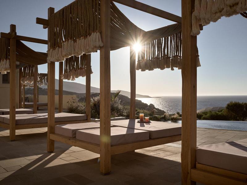 Lettini all'ombra con vista sul mare al tramonto vicino alla piscina.