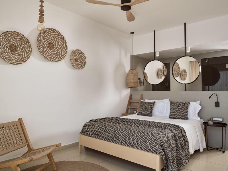 Camera da letto moderna con letto in legno, specchi rotondi e cestini decorativi a parete.