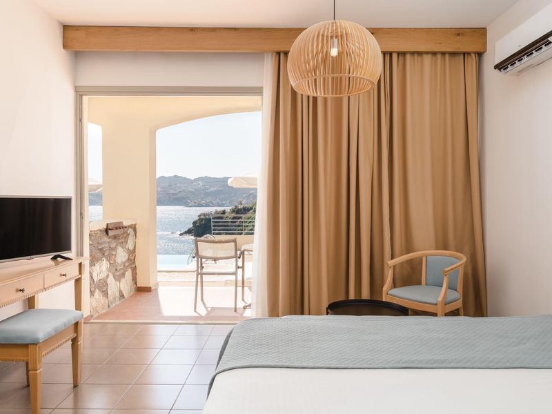 Camera d'hotel luminosa con balcone e vista sul mare.