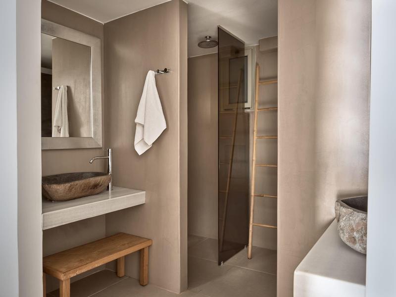 Bagno moderno con lavabo, sgabello in legno e doccia a filo pavimento.