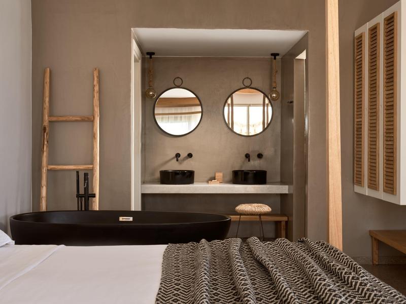 Camera moderna con vasca nera e doppio lavabo con specchi rotondi.