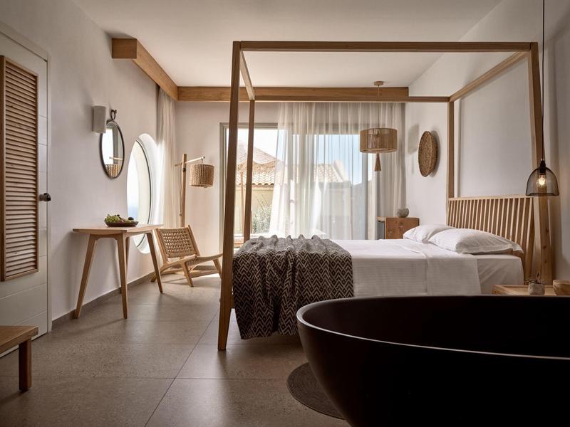 Camera d'albergo moderna con letto a baldacchino, dettagli in legno e grande finestra.