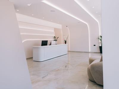 Modern, minimalist reception area with white desk and indirect lighting