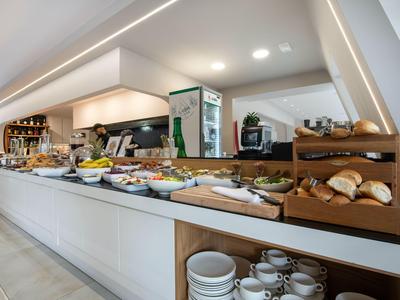 Buffet con una variedad de productos para el desayuno y vajilla en un hotel moderno.