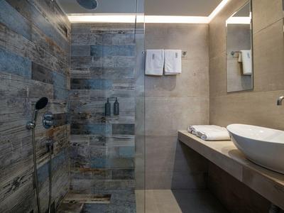 Modern bathroom with rain shower, gray tiles, and countertop with sink.