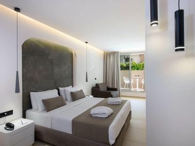 Modern hotel room with double bed, balcony, and minimalist decor.