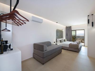 Bright hotel room with bed, sofa, wardrobe, and balcony view