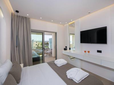 Modern hotel room with double bed, flat-screen TV, and balcony access with sea view.