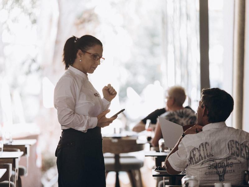 Waitress takes orders from guests in a bright restaurant.