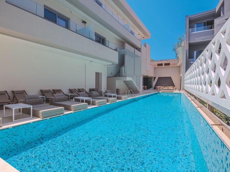 Modern outdoor hotel pool with lounge chairs and blue sky in the background.
