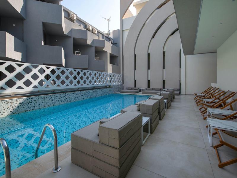 Modern pool area with lounge chairs and seating in a hotel.