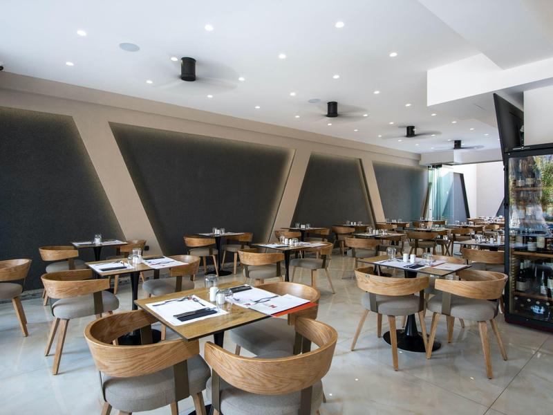 Modern bright dining area with wooden furniture and large windows in a hotel.