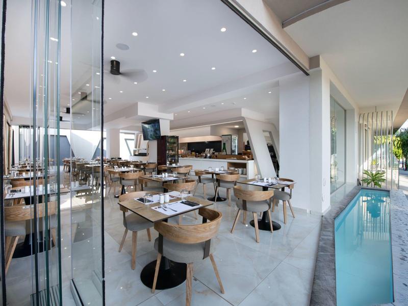 Modern breakfast room with tables, chairs, and view of a small pool.