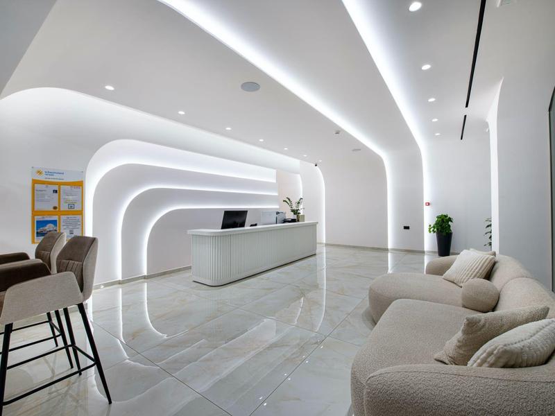 Modern hotel lobby area with curved LED light lines and comfortable seating.