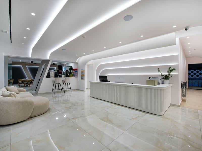 Modern hotel reception with white minimalist design and stylish seating areas.
