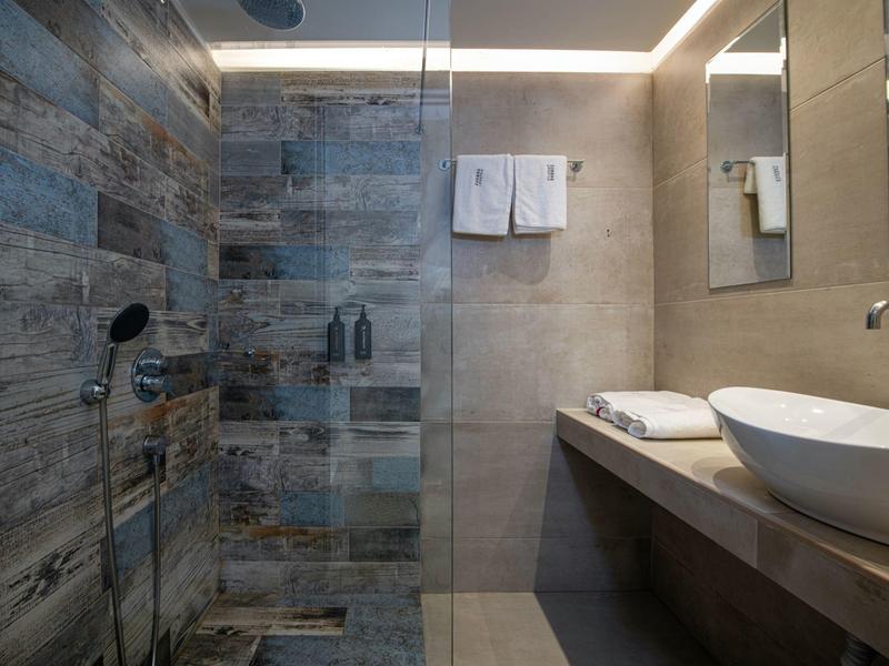 Modern bathroom with rain shower, gray tiles, and countertop with sink.