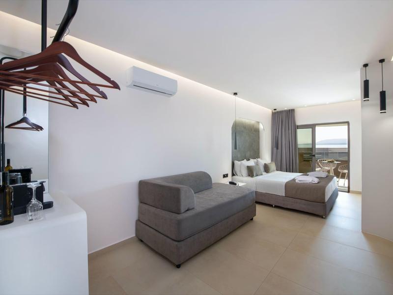 Bright hotel room with bed, sofa, wardrobe, and balcony view