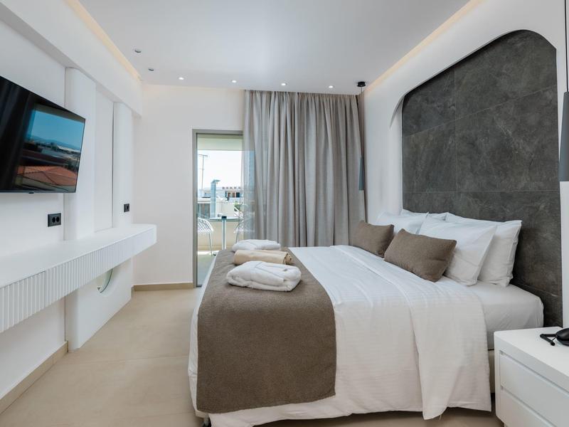 Modern hotel room with double bed, bright interior, and balcony view