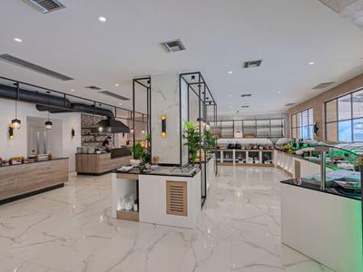 Großer, moderner Verkaufsraum mit hellen Fliesen, vielen Pflanzen und Glasvitrinen.