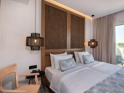 Modern eingerichtetes Hotelzimmer mit Doppelbett, Holzmöbeln und Terrasse mit Blick.