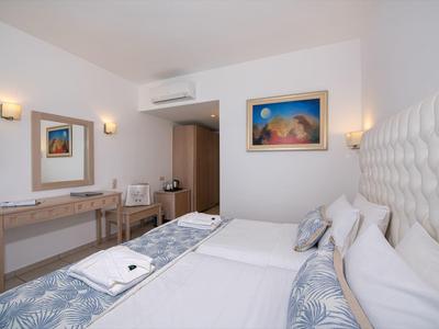 Modernes Hotelzimmer mit zwei Betten, Schreibtisch, Spiegel und Kunst an der Wand.