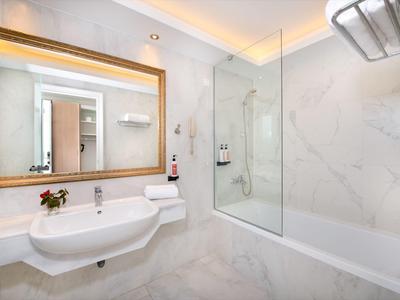 Modernes Badezimmer mit weißer Badewanne, Waschbecken und großem Spiegel mit Holzrahmen.