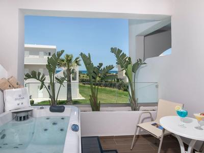 Moderner Balkon mit Whirlpool, Blick auf grüne Gartenanlage und blauen Himmel.