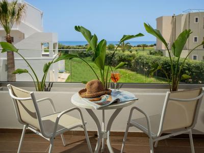 Balkon mit Glasgeländer, Tisch mit Hut und Getränk, Blick auf Garten und Meer